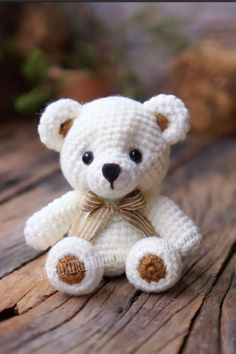 a white crocheted teddy bear sitting on top of a wooden table