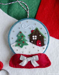 a handmade ornament with a house and tree on it next to a pair of scissors