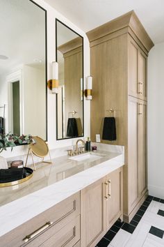 a large bathroom with marble counter tops and gold accents on the mirror, along with black and white tile flooring