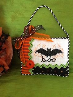 a cross - stitch bag with a bat hanging from it's side on a green surface