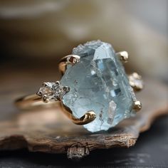 a close up of a ring with an aquamarine colored stone in the middle and two diamonds on each side