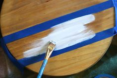 a paintbrush is sitting on top of a wooden table with blue tape around it