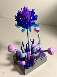 a purple and blue flower sitting on top of a gray block with lots of pink flowers