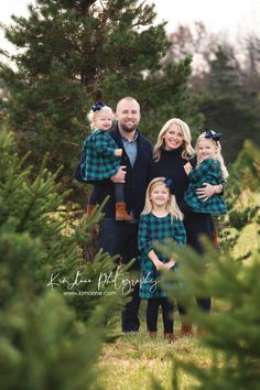 a family posing for a photo in front of some trees at the christmas tree farm