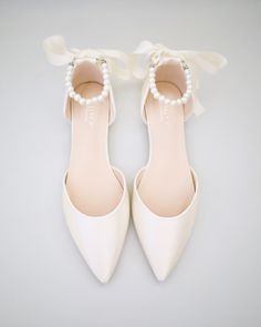 a pair of white high heels with pearls on the toe and bow at the back