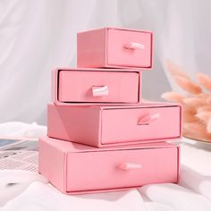 three pink boxes stacked on top of each other in front of a stuffed animal toy