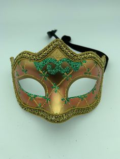 "This is a very nice original handmade and hand painted Venezia masquerade face mask made in Italy. The design on the shiny gold and orange face mask features turquoise blue and multi-color glitter with a border of gold lace and gold rope around the edges. It comes with a black ribbon tie and is stamped on the back \"Original Hand Painted Made in Italy Venezia\". The mask measures approximately 6 5/8\" long and 3 3/4\" wide and is in very good preowned condition with light wear on the back of th Adjustable Masquerade Mask For Mardi Gras, Venetian Masks For Mardi Gras Carnival, Green Masquerade Mask For Mardi Gras, Multicolor Masks And Prosthetics For Masquerade And Carnival, Multicolor Masks And Prosthetics For Carnival Masquerade, Green Masks For Carnival Costume Party, Fantasy Carnival Masquerade Masks, Adjustable Masks For Carnival Costume Party, Halloween Eye Mask As A Gift