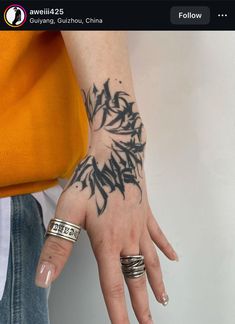 a woman's hand with tattoos on it and two rings around her wrist,