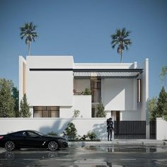 a black car parked in front of a white building with palm trees on the side