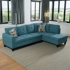 a blue sectional couch in front of two windows with curtains on either side and an area rug underneath it