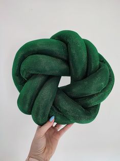 a hand holding up a green fabric wreath