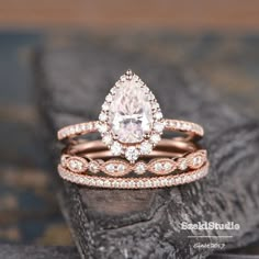 two wedding bands with a pear shaped diamond in the center and side stones on each band