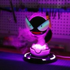 a small toy sitting on top of a table next to a purple light in the dark