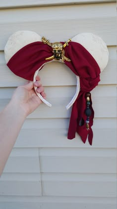 a person holding onto a mickey mouse ears headband that is attached to the side of a house