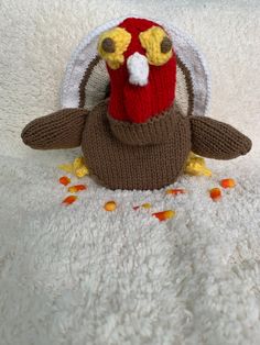 a stuffed turkey with a knitted hat on it's head sitting on a white blanket