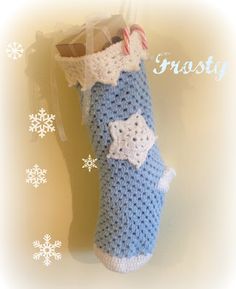 a crocheted stocking hanging on a wall with snowflakes in the background