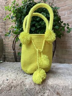 a yellow purse sitting on top of a rock next to a potted green plant