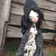 a doll is sitting on the ground next to a wooden fence