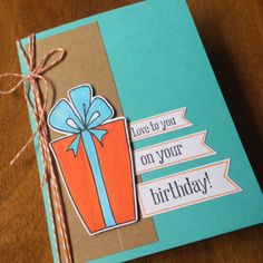 a handmade birthday card with a blue and orange gift box on it's side