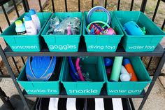 three bins filled with different types of toys and cleaning supplies sitting on top of a metal cart