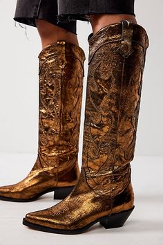 Have a major moment in these tall metallic cowboy boots. **Features:** Tall style, pull-on design, leather uppers, pointed toe, crinkled metallic finish, embroidered details, dipper toplines, pull straps, block heel **Why We | Moody Metallic Cowboy Boots by FP Collection at Free People in Gold, Size: US 8 Gold Cowboy Boots, Metallic Cowboy Boots, Snakeskin Cowboy Boots, Hunter Wellies, Black Cowboy, Mens Cowboy Boots, Western Boots Women, Free People Shoes, Cowgirl Outfits