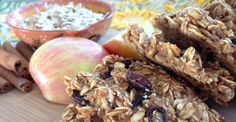 granola bars are stacked on top of an apple, cinnamon sticks and bowl of oatmeal