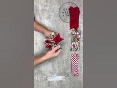 the person is holding two red and white christmas stockings with bows on them, next to an envelope