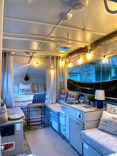 the inside of an rv with couches, tables and lights hanging from the ceiling