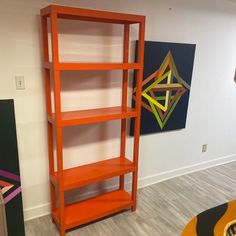 an orange shelving unit next to a painting on the wall