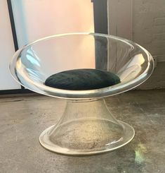 a glass bowl sitting on top of a metal stand with a black cushion in it