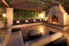 an outdoor living area with couches, tables and a fire place in the center