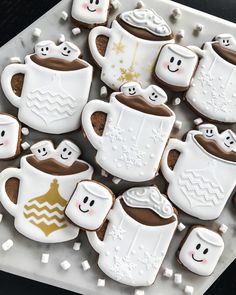 decorated cookies in the shape of coffee mugs and marshmallows on a tray