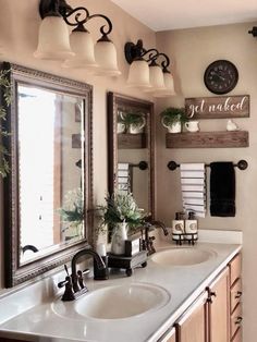 a bathroom with two sinks, mirrors and lights on the wall above them is decorated with greenery