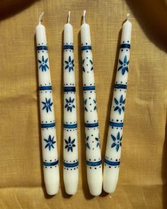 three candles with blue and white designs on them are sitting next to each other in front of a brown cloth