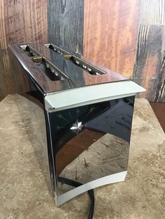 a black and silver toaster sitting on top of a counter next to a wooden wall