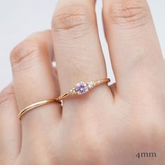 a woman's hand wearing a gold ring with an amethoraite and diamond