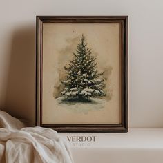 a painting of a christmas tree on a shelf next to a white blanket and pillow