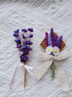 two different types of flowers are on a white surface with lace and ribbon tied around them