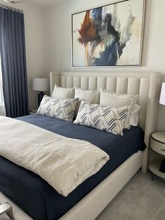 a large bed sitting in a bedroom next to a window with blue drapes on it