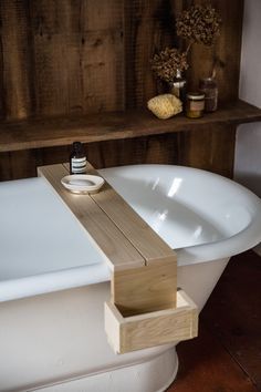 a white bath tub sitting next to a wooden shelf