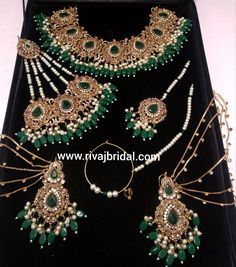 green and white jewelry set on display in a black velvet case with pearls, beads and stones