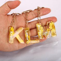 a person is holding two key chains with the letters k and f on them, in front of a white background