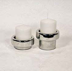 two white candles sitting on top of each other