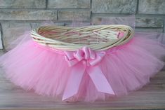 a pink tutule sitting on top of a wooden table next to a brick wall