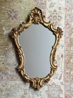 an ornate gold framed mirror sitting on top of a rug