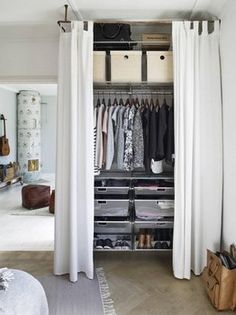 an open closet with white curtains and clothes