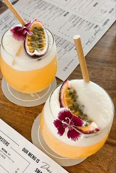 two glasses with drinks sitting on top of a wooden table next to paper menus