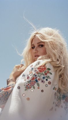 a woman with long blonde hair is wearing a white dress and has flowers on it