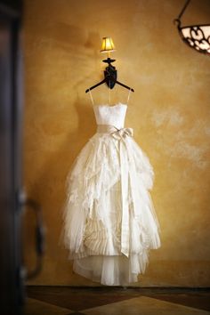 a white dress hanging on a wall next to a lamp