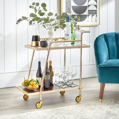 a bar cart with drinks and glasses on it in front of a wall mounted art